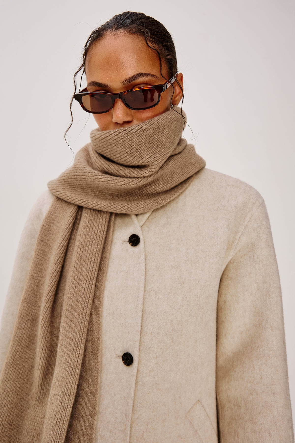 Alps is a cashmere scarf in Oat colorway. Front view featured on model.