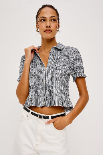 Alton Top in Cotton Poplin With Smocked Body Boxy Cropped Fit Collar Front Buttons Short Puff Sleeves and Ruffle Trim in Black Gingham Colorway - Upper Body Front View Featured on Model