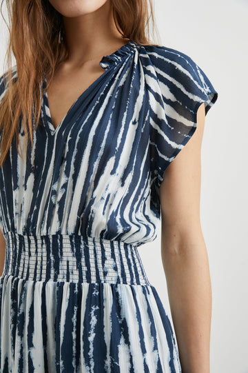 Amellia Short-Sleeve Midi Dress with Smocked Waist and Collar, V Neck, and a Tiered Skirt in Indigo Nile Stripe Colorway, White and Indigo Streaks - Front View Featured on Model