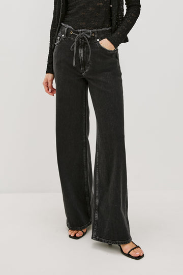 Angeleno mid rise slouchy wide leg jean with a drawstring waist tie, gromets and a raw edge waistband in a black wash Ash Black - front view featured on model.