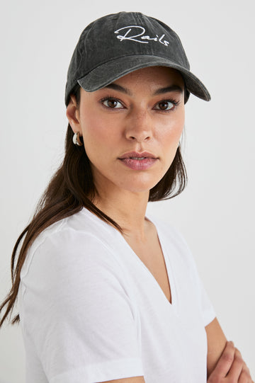 Anniversary Baseball Cap with an Adjustable Back Strap, Front Text, Rails, and Back Text, Est 2009, in Washed Black Colorway, with White Text - Front View Featured on Model