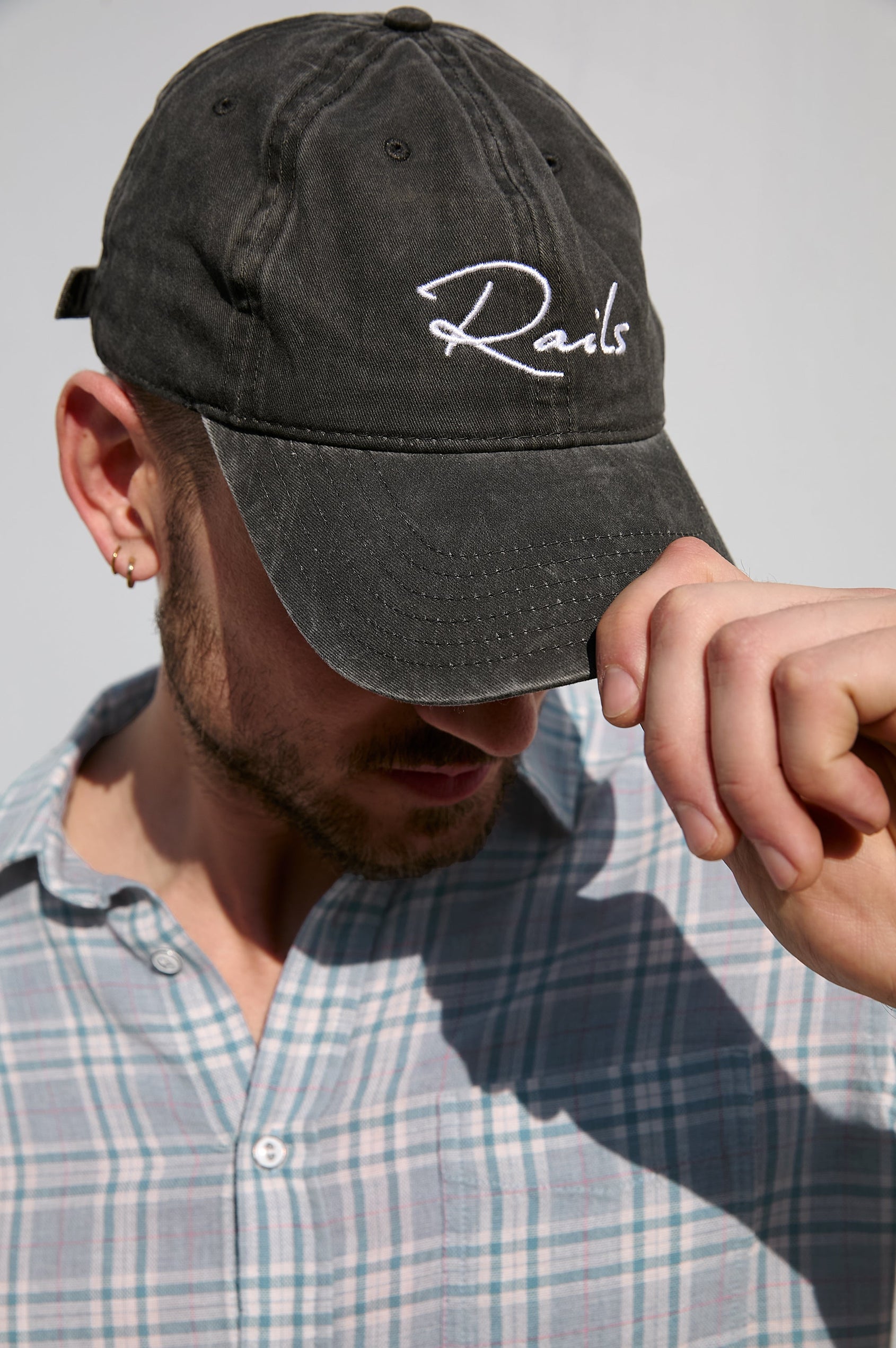 Anniversary Baseball Cap with an Adjustable Back Strap, Front Text, Rails, and Back Text, Est 2009, in Washed Black Colorway, with White Text - Front Angled View Featured on Model