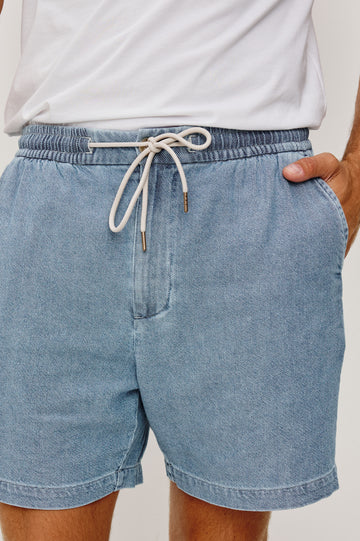 Archer Short in Unlined Cotton Linen With Relaxed Fit, Adjustable Waist Drawstring Ties, Side Pockts, and 6-Inch Inseam in Medium Wash Indigo Colorway - Close up View Featured on Model