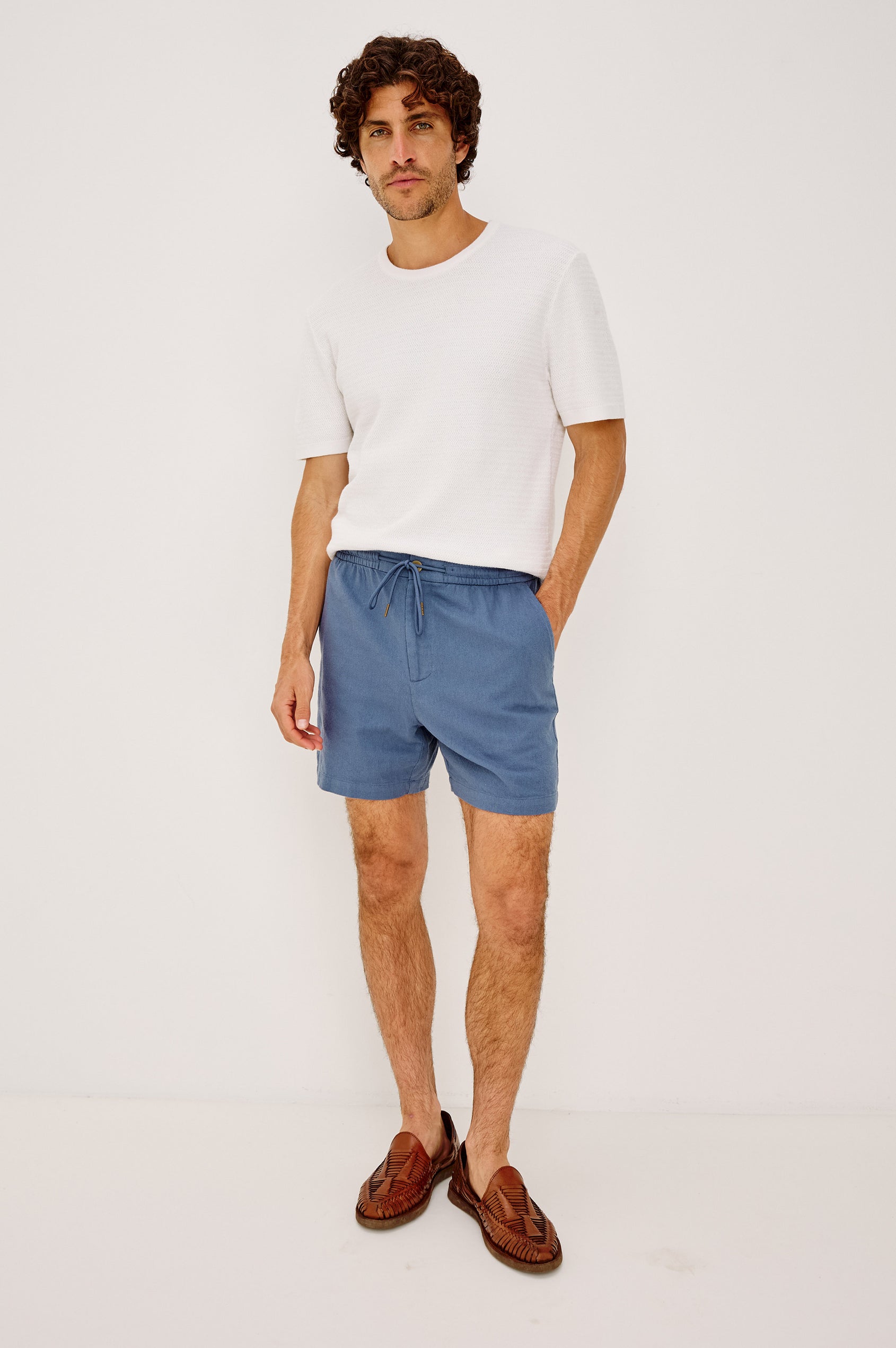 Archer Short in Heavy Linen With Relaxed Fit, Elastic Drawstring Waist, Front Zip Fly, 6″ Inseam, and Side Pockets in Washed Blue Colorway - Full Body Front View Featured on Model