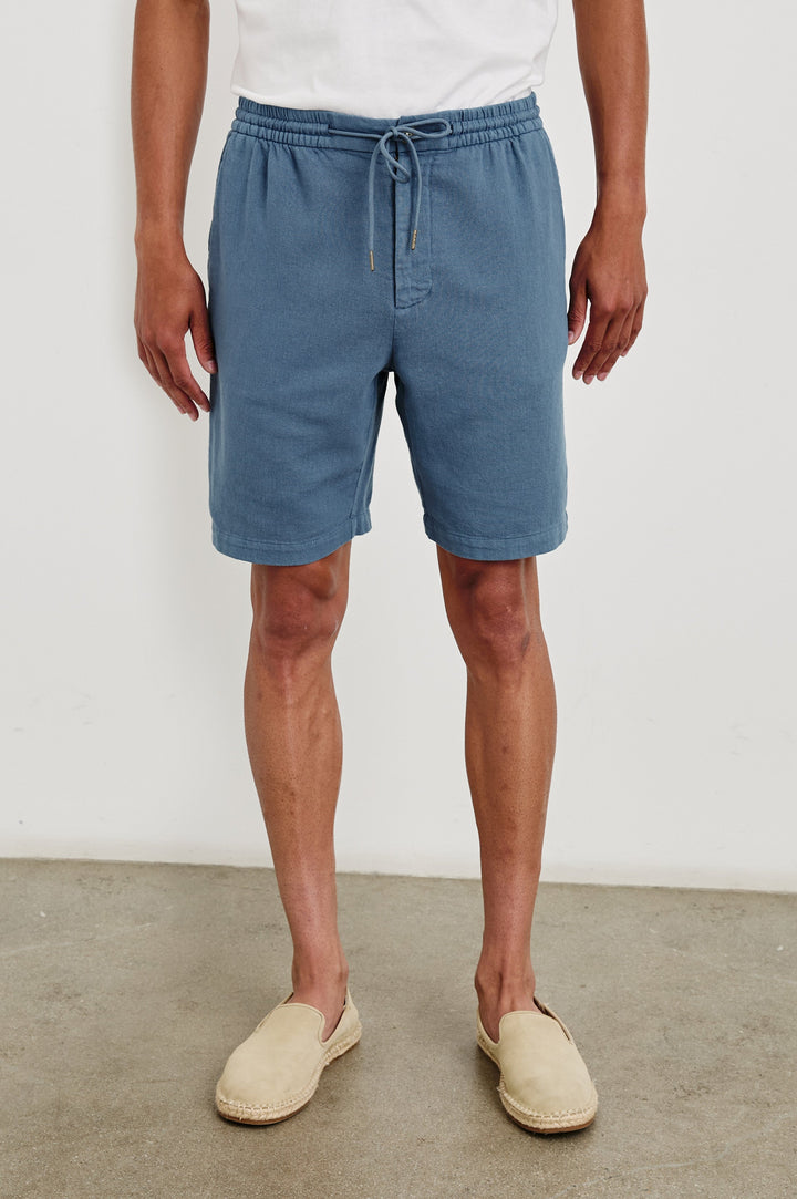 Archer long length cotton short with adjustable drawstring and front button closure in Washed Blue - front view on model