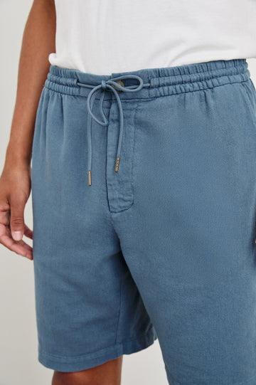 Archer long length cotton short with adjustable drawstring and front button closure in Washed Blue - front view on model