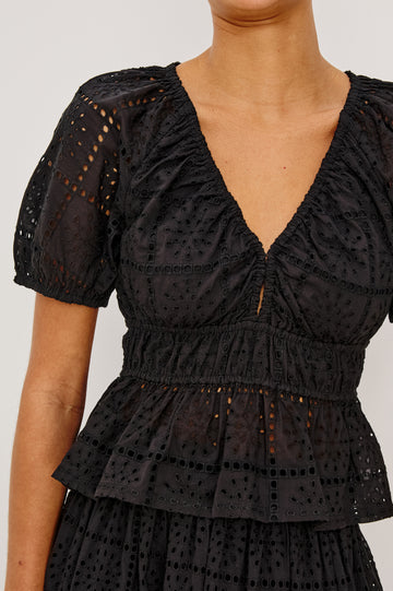 Argenta Top in Cotton Voile With Embroidered Pattern, Short Puff Sleeves, Hook-and-Eye Closure, Elastic V-Neckline and Waist, and Peplum Hem in Black Grid Embroidery Colorway - Upper Body Close Up View Featured on Model