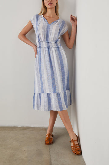 Ashlyn Short Sleeve Midi Dress with a V neck with Ties, a Smocked Waist and a Ruffle Tier at the Hem in Nevis Stripe Colorway, Vertical Stripes in Blue on White - Front Full Body View Featured on Model
