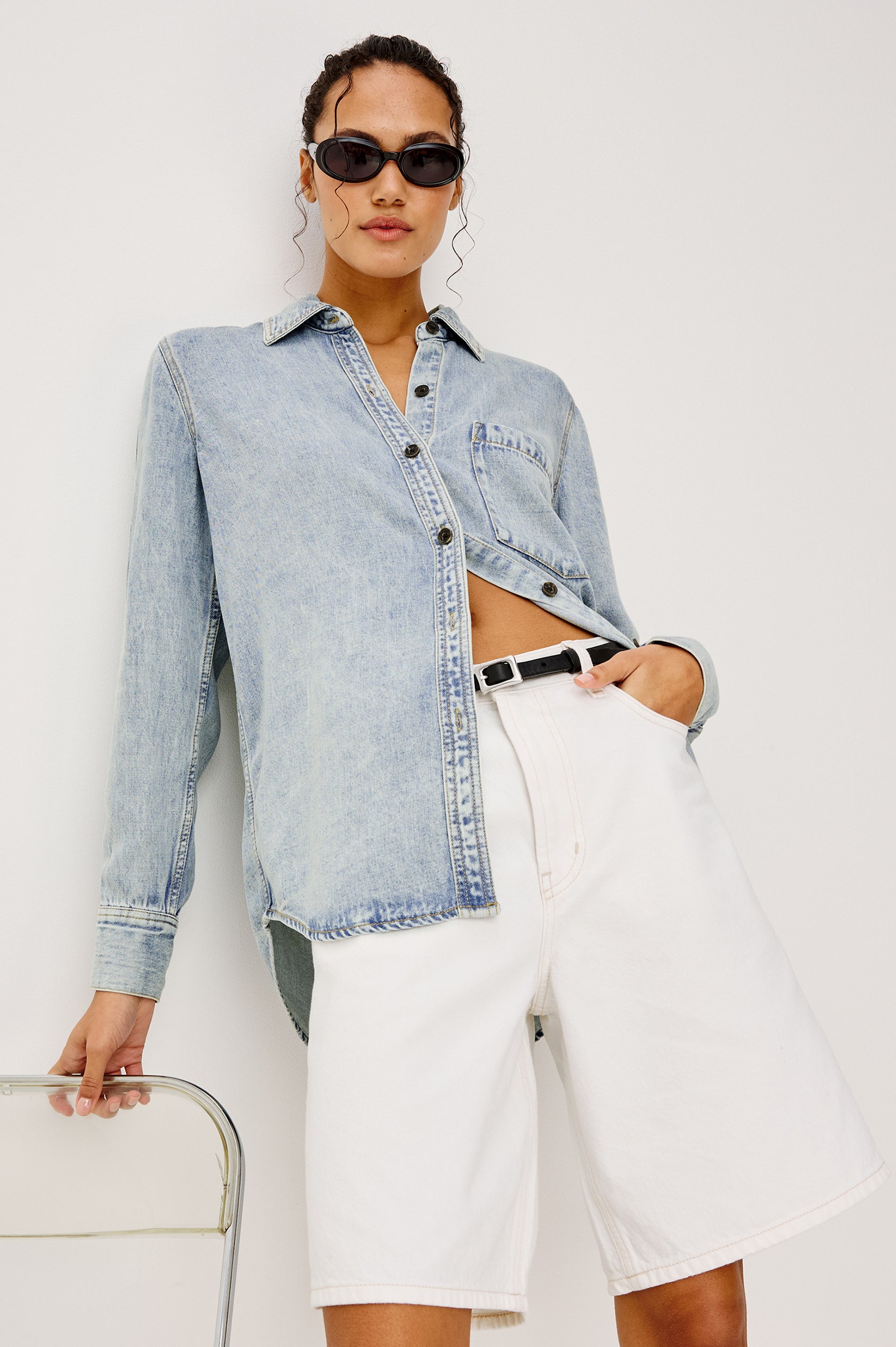 Atticus Long-Sleeve Denim Style Button Up with Chest Patch Pocket in Bleached Indigo Colorway - Upper Body Front View Featured on Model Standing Next To Chair