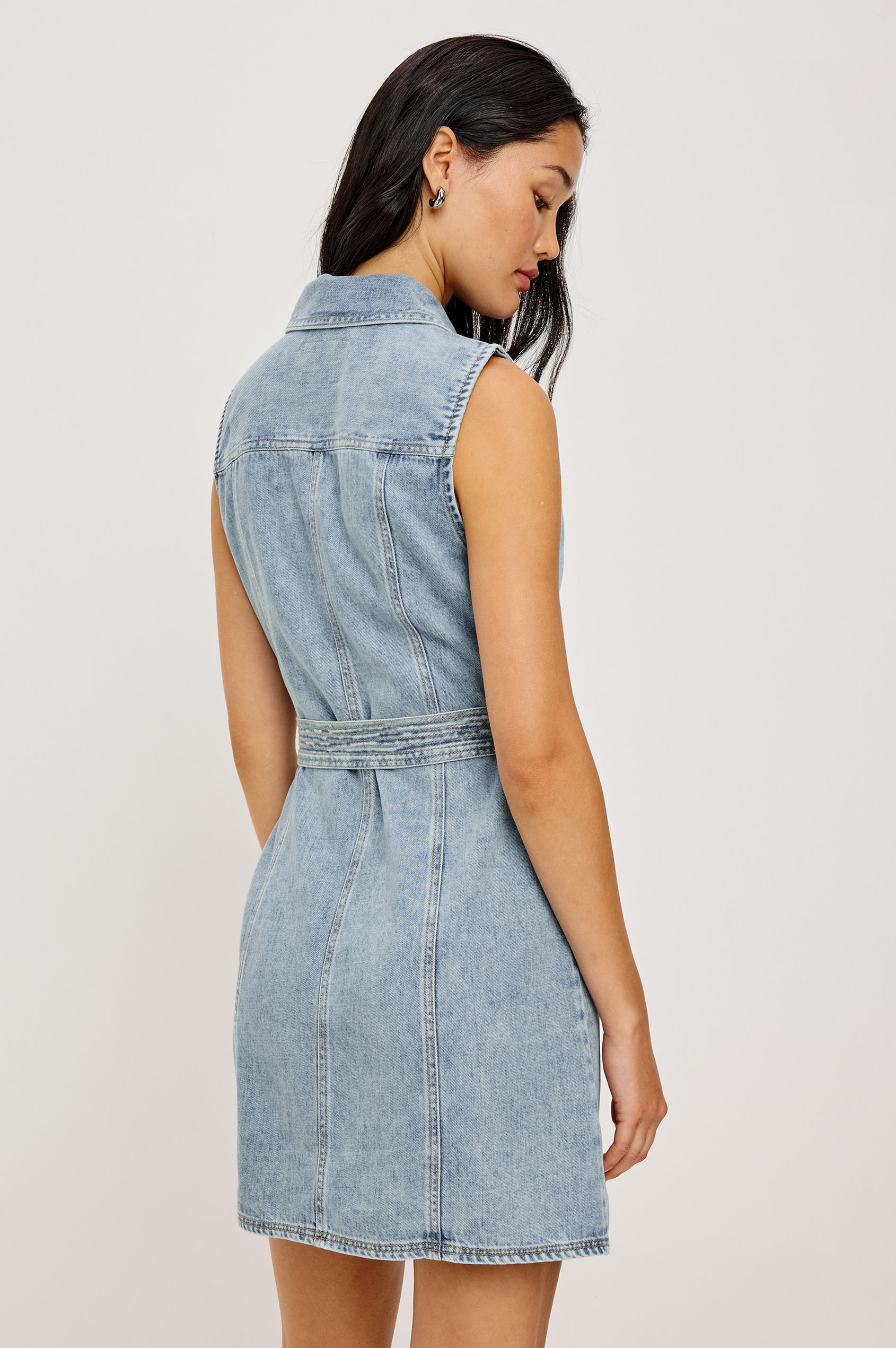 Aurora Sleeveless Mini Dress in TENCELâ„¢Denim With Collar Front Exposed Zipper Adjustable Belted Ties Side Flap Pockets in Faded Indigo Colorway - Upper Body Back View Featured on Model