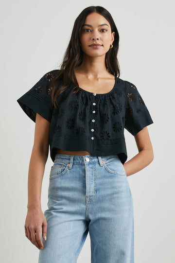 Bambina Short-Sleeve Cropped Top with a Scoop Neck, Buttons Down the Front, and Floral Eyelets in Black Colorway - Front View Featured on Model 