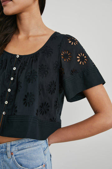 Bambina Short-Sleeve Cropped Top with a Scoop Neck, Buttons Down the Front, and Floral Eyelets in Black Colorway - Front View Featured on Model 