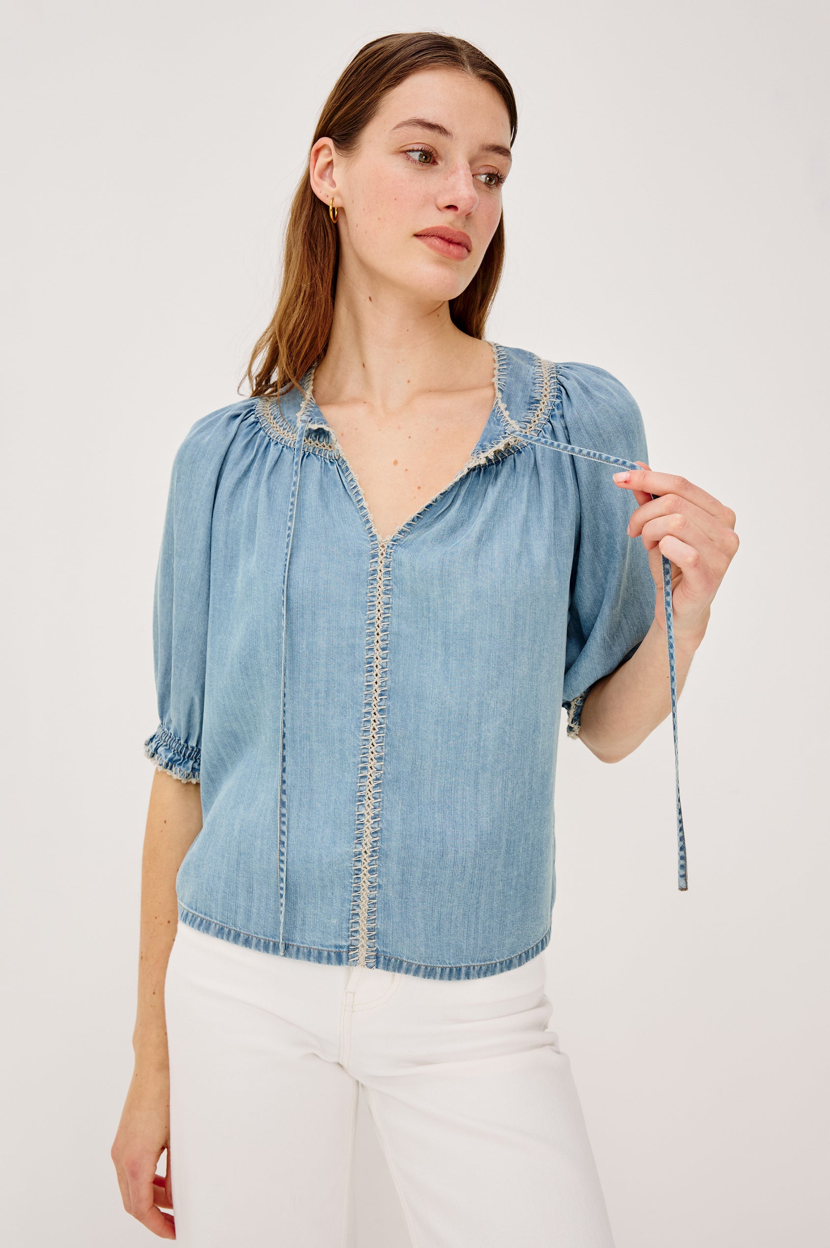 Belina Peasant Top in TENCELâ„¢ Denim With Gathered V-Neckline With Self Ties Blanket Stitch Embroidered Trim Loose Fit and Elbow-Length Puff Sleeves With Elastic Cuffs - Upper Body Front View Featured on Model
