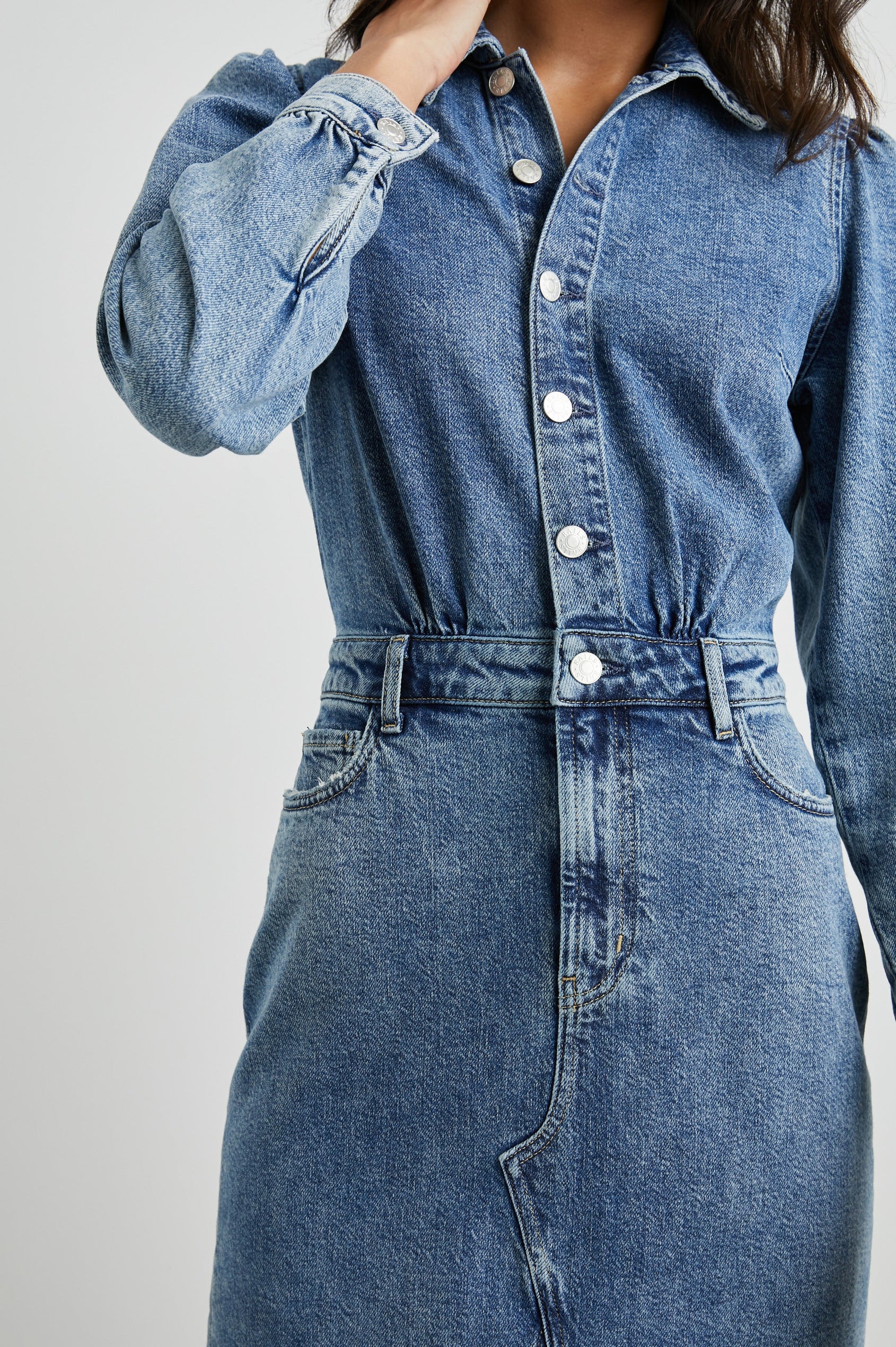Beverly Long Sleeve Denim Knee Dress with a Back Vent, Belt Loops, a Button and Zipper Closure for the Skirt and Button Closure on the Bodice, a Collar, two Front Pockets plus a Coin Pocket and Two Back Patch Pockets in West Coast Colorway, a Blue - Front View Featured on Model