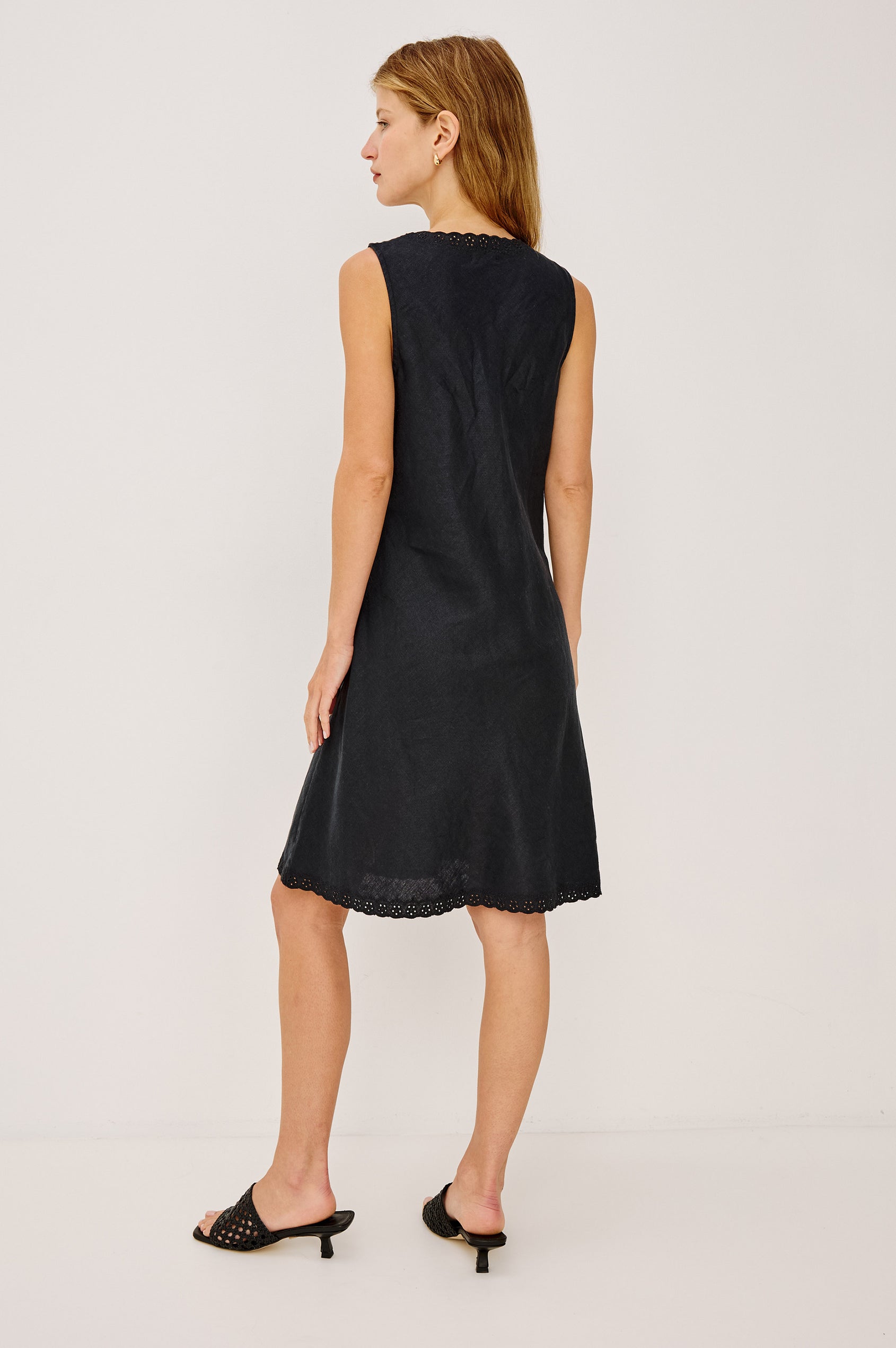 Bex Mini Dress in Linen With Bias Cut, A-Line Skirt, Embroidered V-Neckline and Hem, and Side Seam Zipper in Black Linen Colorway - Full Body Back View Featured on Model