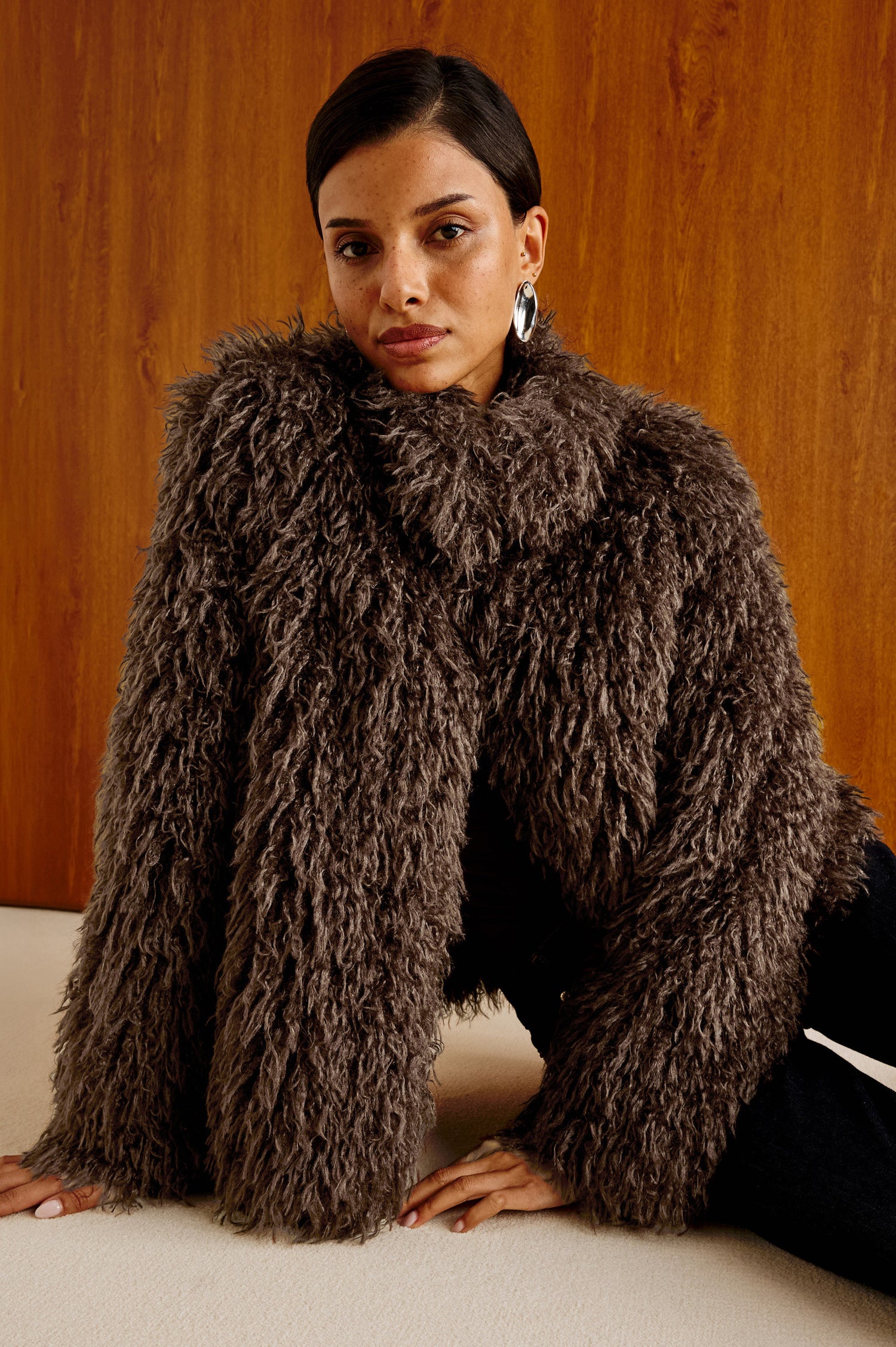Blisse Jacket in Faux Mongolian Fur With Boxy Slightly Cropped Cropped Silhouette, Collar, Satin-Like Lining, Side Pocketts, and Front Hook-And-Eye Closure in Espresso Colorway - Upper Body Front View Featured on Model Stylized