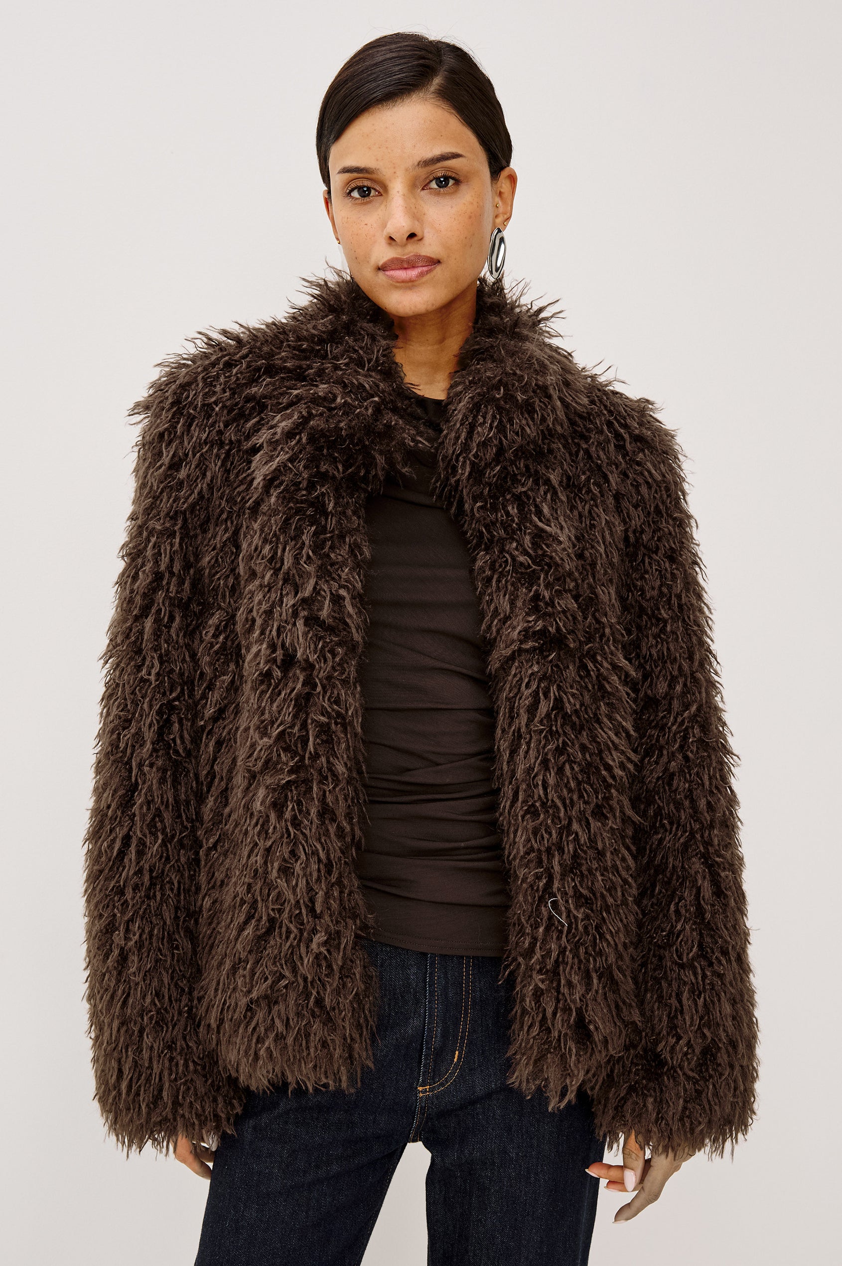 Blisse Jacket in Faux Mongolian Fur With Boxy Slightly Cropped Cropped Silhouette, Collar, Satin-Like Lining, Side Pocketts, and Front Hook-And-Eye Closure in Espresso Colorway - Upper Body Front View Featured on Model