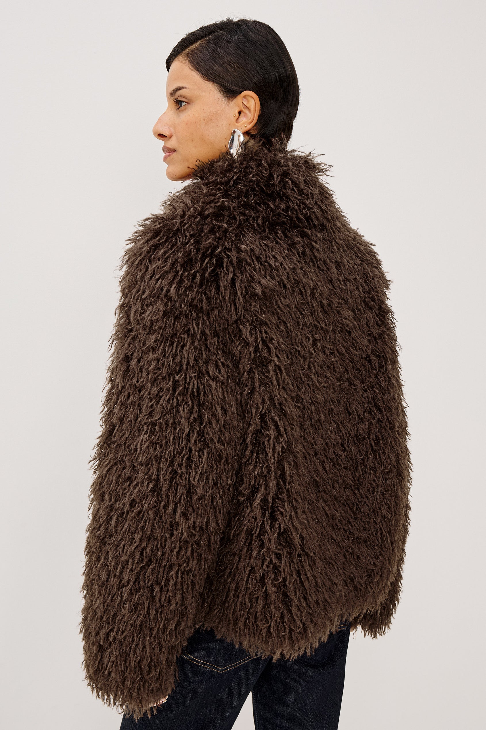 Blisse Jacket in Faux Mongolian Fur With Boxy Slightly Cropped Cropped Silhouette, Collar, Satin-Like Lining, Side Pocketts, and Front Hook-And-Eye Closure in Espresso Colorway - Upper Body Back View Featured on Model