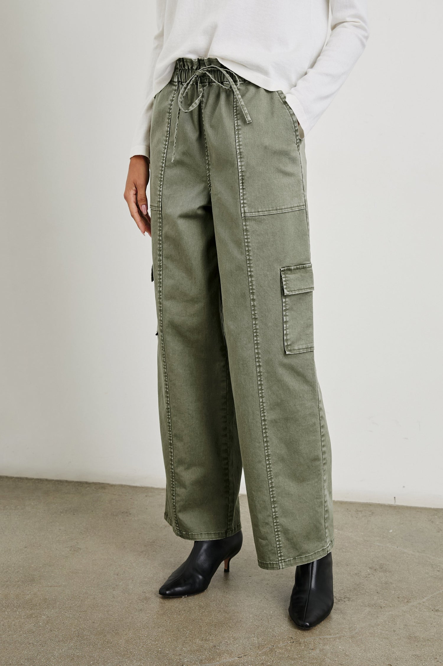 Bodie Pants with a Drawstring Waist, Front and Back Center Vertical Leg Seams, Two Front Pockets, Two Flap Side Pockets and Two Back Welt Pockets in Dark Olive Colorway - Front View Featured on Model  