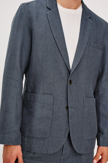 The Bond is a single breasted blazer with two buttons, one chest pocket and two patch pockets in a blue Meridian colorway. Front detail view featured on model.