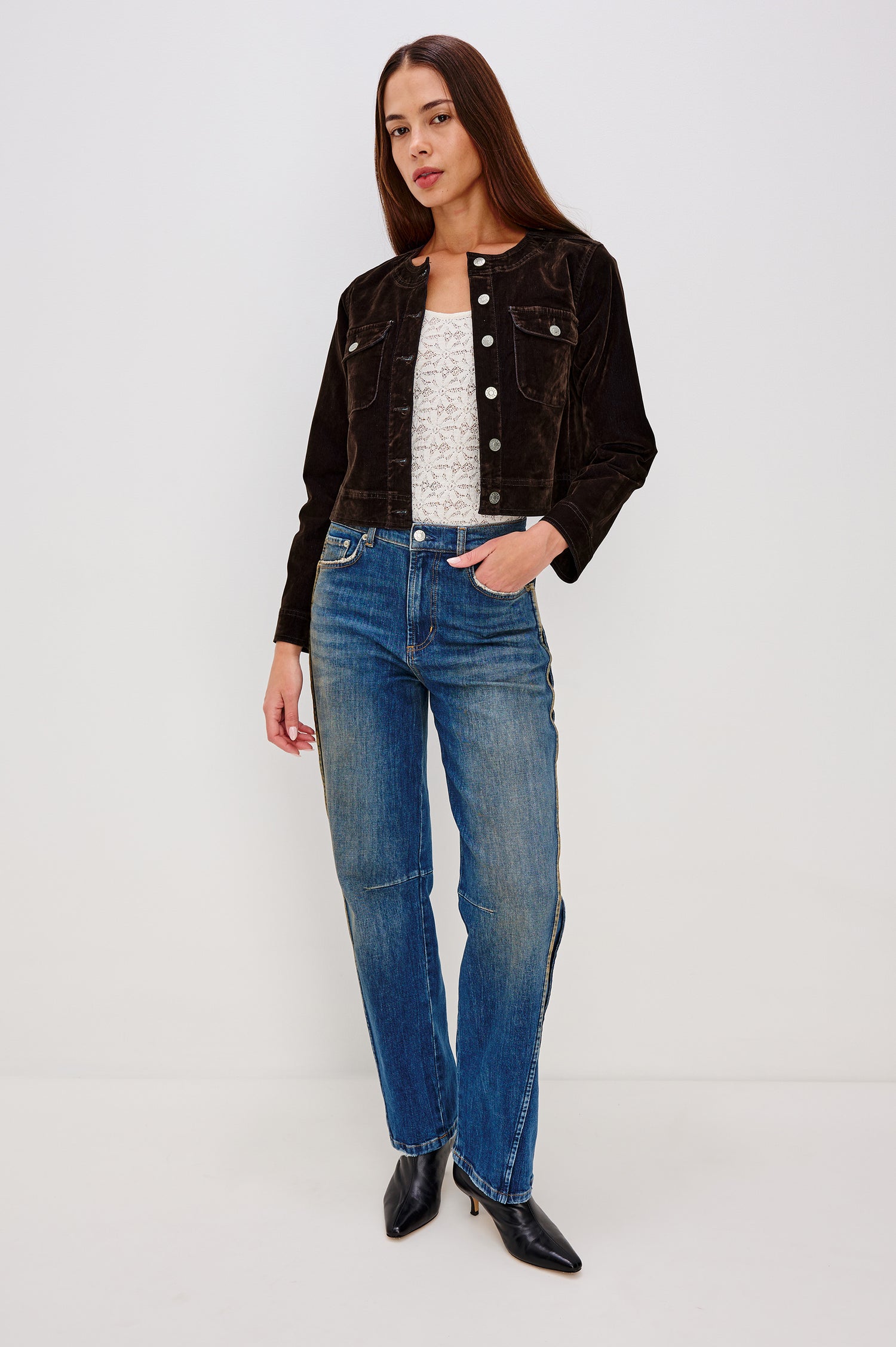 Capistrano Cropped Jacket in Chocolate Velvet Flocked Denim With Crew Neckline, Indigo Wash, Front Buttons, Buttoned Chest Pockets, and Long Sleeves in Chocolate Flocking Colorway - Full Body Front View Featured on Model