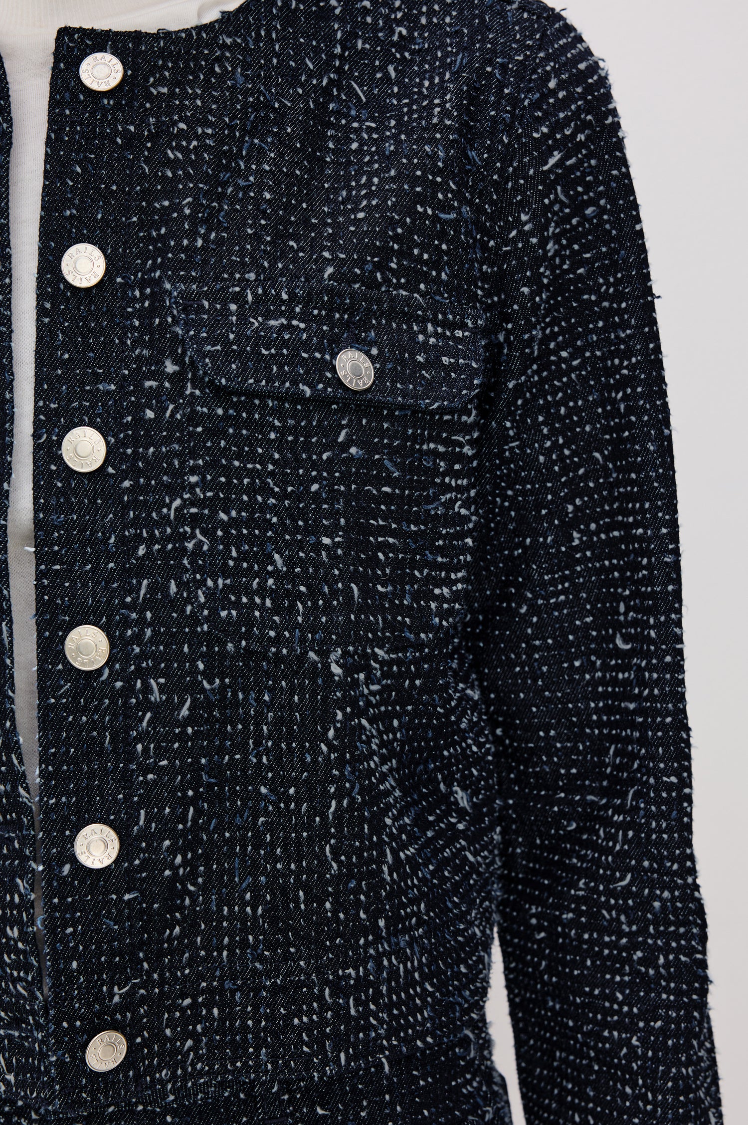Capistrano Cropped Jacket in Denim Tweed Texture With Crew Neckline, Front Buttons, Buttoned Chest Pockets, and Long Sleeves in Denim Tweed Colorway - Upper Body Front Close Up View Featured on Model
