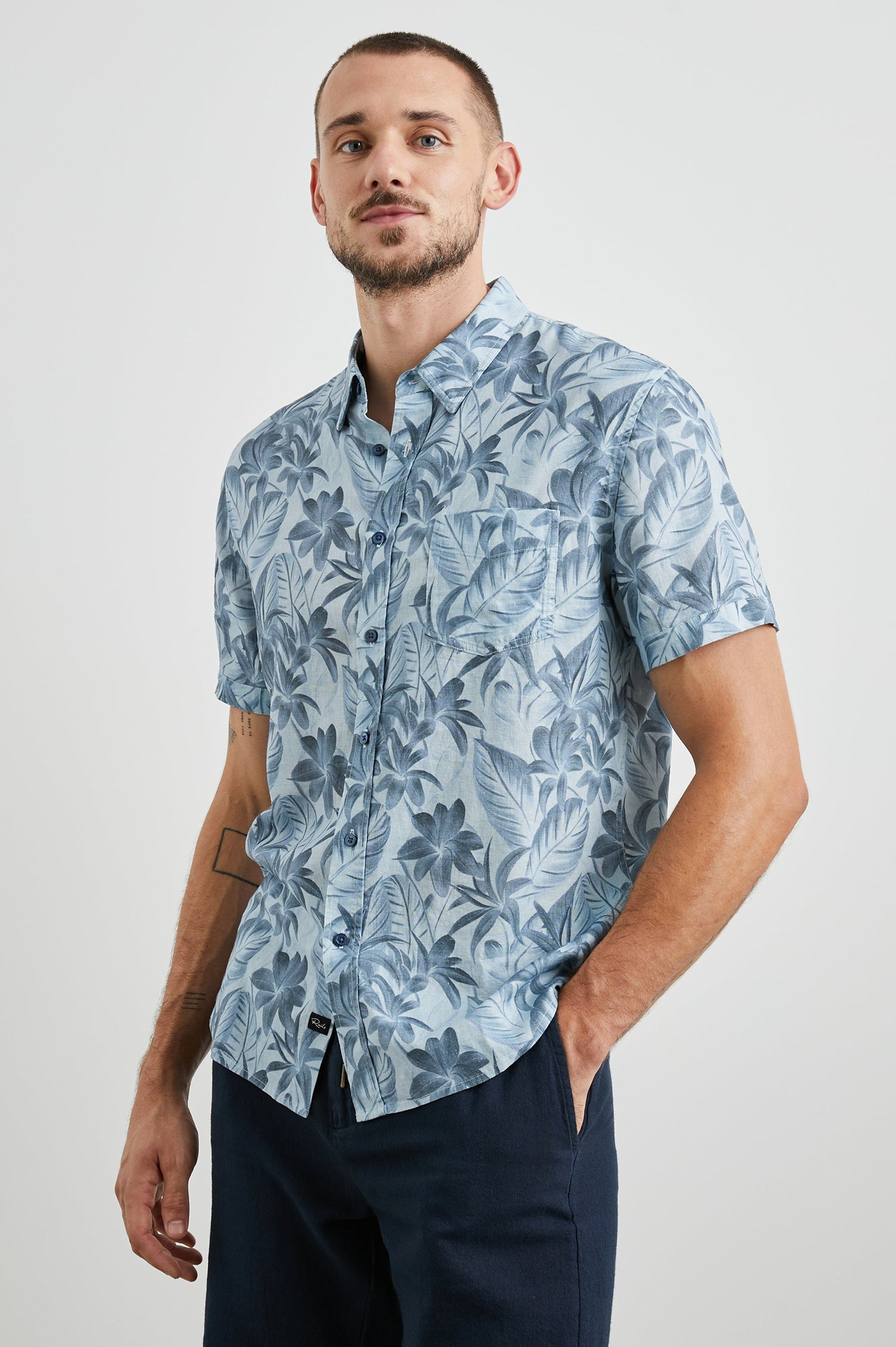 Carson Short Sleeve Button Up with a Chest Patch Pocket in Jungle Garden Reflection Colorway, Flowers and Leaves in Blues on Light Blue - Front View Featured on Model