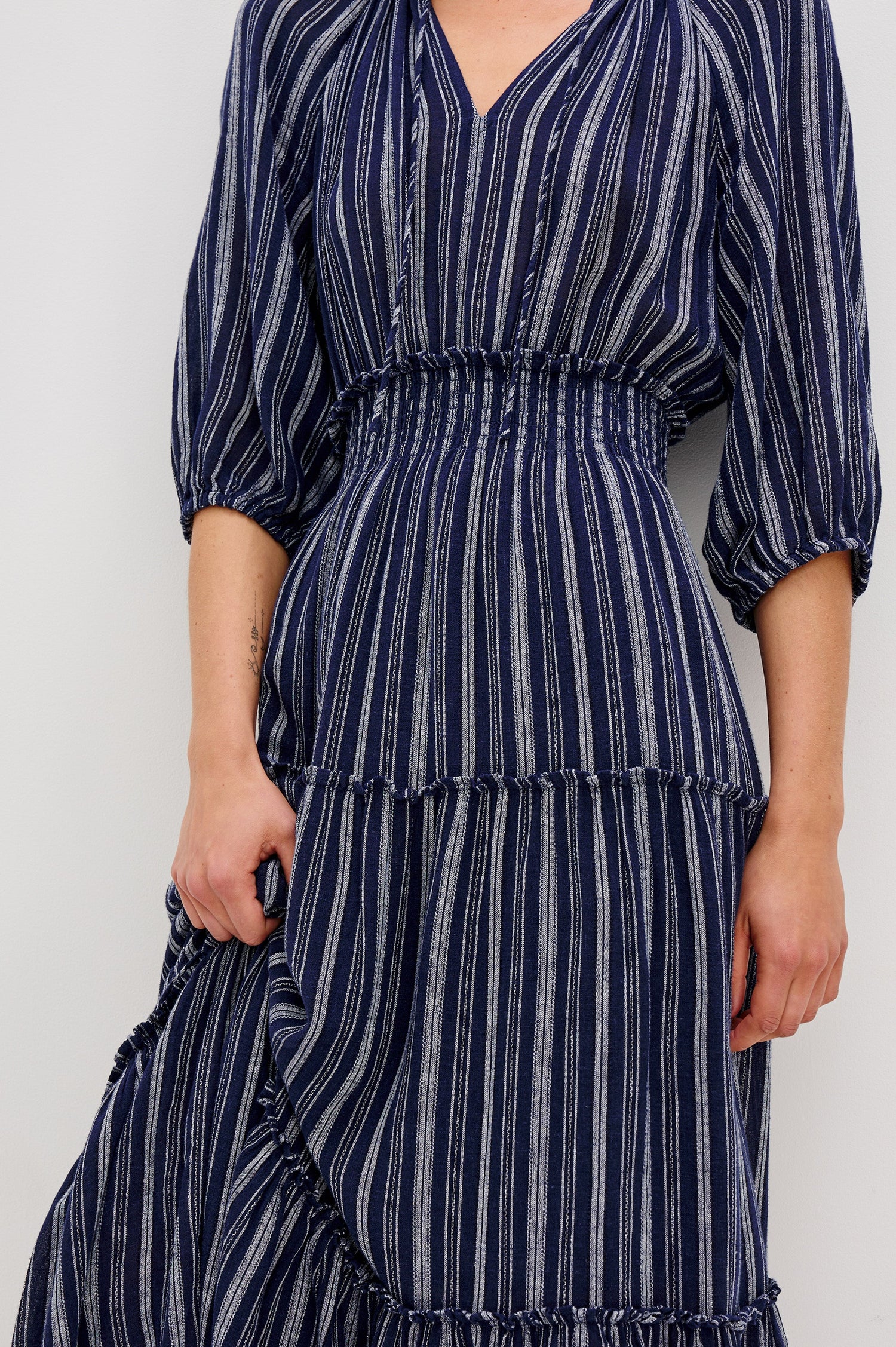Caterine Maxi Dress with Mid-length Sleeves, a V neck, a Shirred Collar with a tie, a Smocked Waist, and a Tiered Skirt in Roche Stripe Colorway - close up of details on model