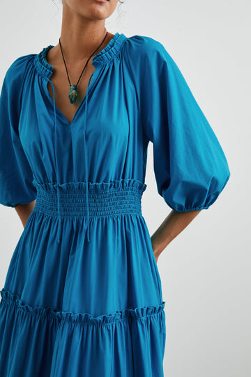 Caterine Maxi Dress with Mid-length Sleeves, a V neck, a Shirred Collar with a tie, a Smocked Waist, and a Tiered Skirt in Turkish Tile Colorway, a blue - Front View Featured on Model