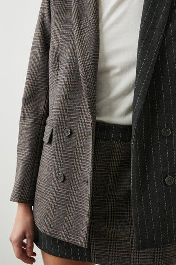 Cody Double-Breasted Blazer with Two Button Closure, Two Front Flap Pockets, and Four-Button Cuffs in Pinstripe Plaid Mix Colorway, the Right Half is a Plaid in Brown, Blue and Red, the left half is White pinstripe on Black - Front View Featured on Model