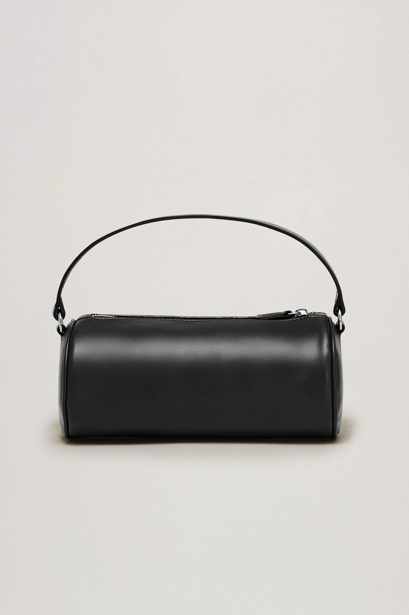 The Como is a mini barrel bag, made from smooth leather with a fixed top strap, a removable and adjustable buckled crossbody strap, a top zip, a side-embossed logo, and a branded interior label, in Black Leather colorway. Front view featured.
