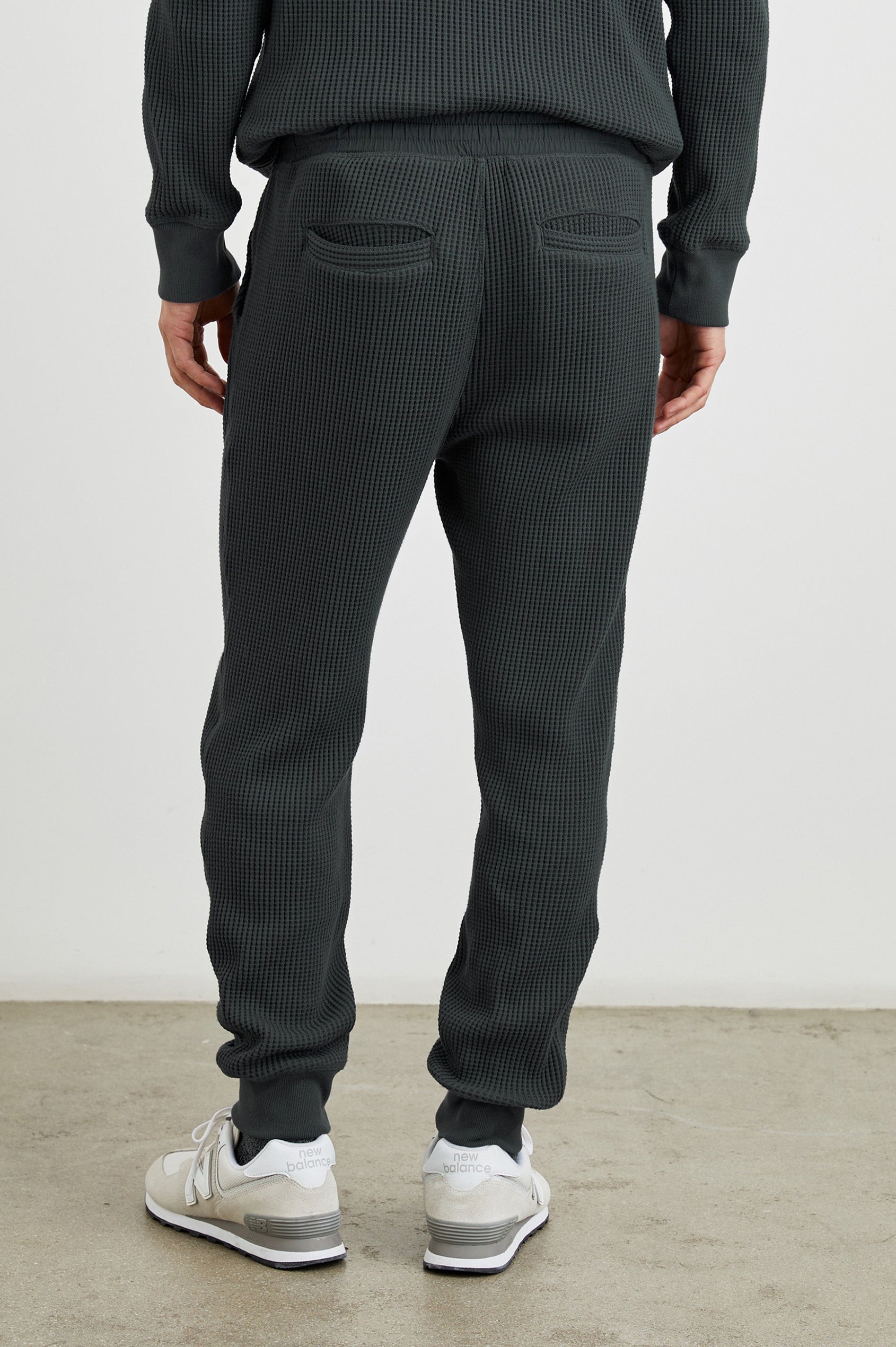 Cooper Waffle Thermal Pants with an Elastic Drawstring Waist, Two Teardrop Front Pockets, Two Back Welt Pockets, Reinforced Knee Patches and Elastic Cuffs in Ink Colorway - Back View Featured on Model