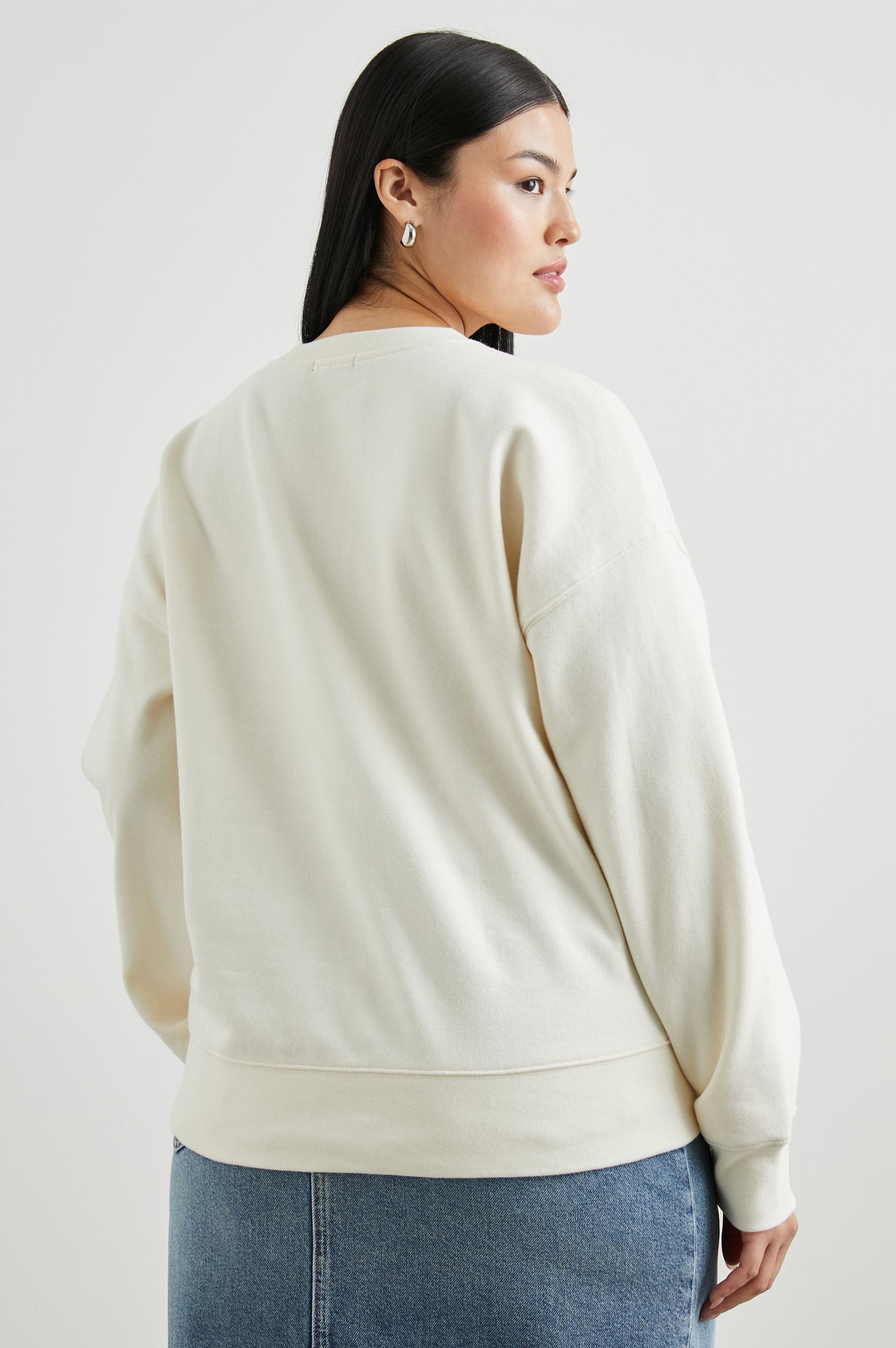 Cosmic Country Club Long-Sleeve Sweatshirt with a Crew Neck and the Front Black Text, Cosmic Country Club, Palm Springs, Rails and Friends 2010, and an Image of a Striped Setting Sun in Orange and Black in Winter White Colorway - Back View Featured on Model  