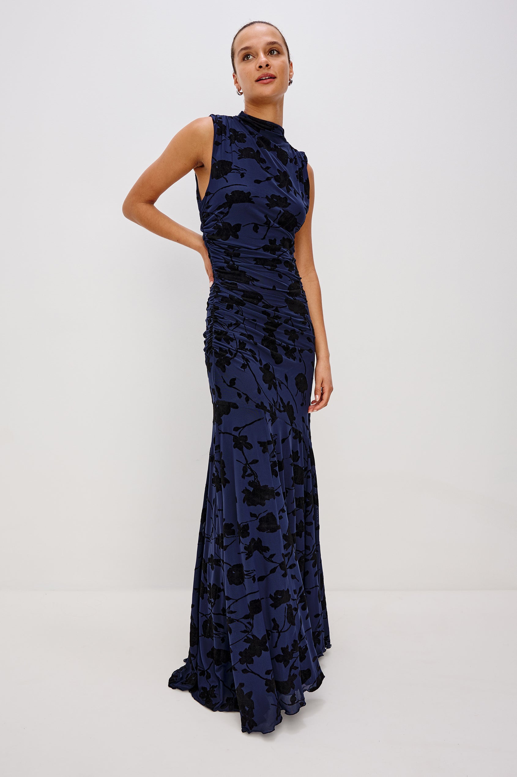 Cosmos Maxi-Length Dress with a Cowl Neck, Sleeveless, Form Fitting with a Ruched Side Seam Detail and an A-line Hem in Navy Tossed Roses Colorway. Full Body Front View Shown on Model.