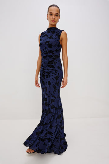 Cosmos Maxi-Length Dress with a Cowl Neck, Sleeveless, Form Fitting with a Ruched Side Seam Detail and an A-line Hem in Navy Tossed Roses Colorway. Full Body Front View Shown on Model.