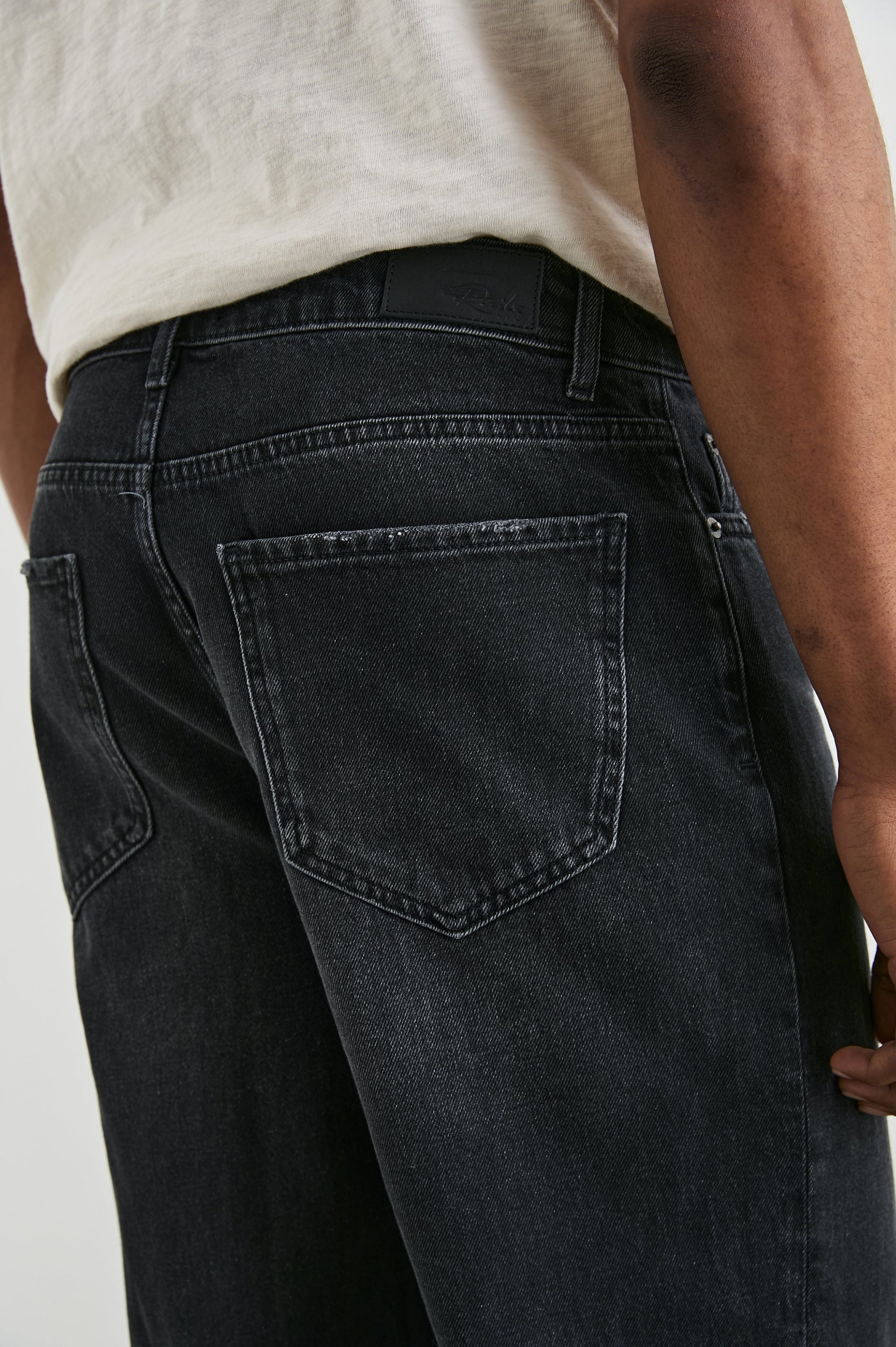 Cutler 90's Loose Jeans with Belt Loops, Two Front Pockets plus a Coin Pocket and Two Back Patch Pockets in Distressed Black Colorway - Back View Featured on Model