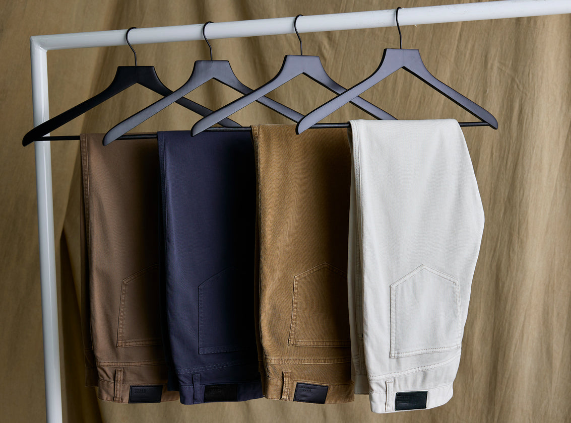 IMAGE OF MULTIPLE PAIRS OF CARVER PANTS HANGING ON HANGERS