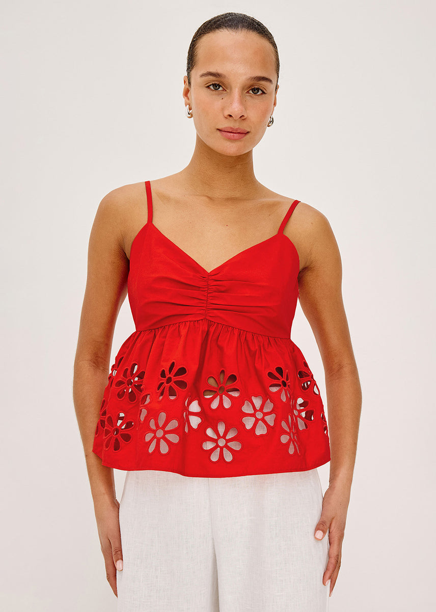 Woman wearing a red top with floral cut-out details on a white background