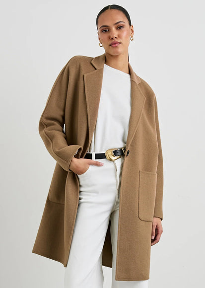 Woman wearing a brown coat over a white outfit on a plain background