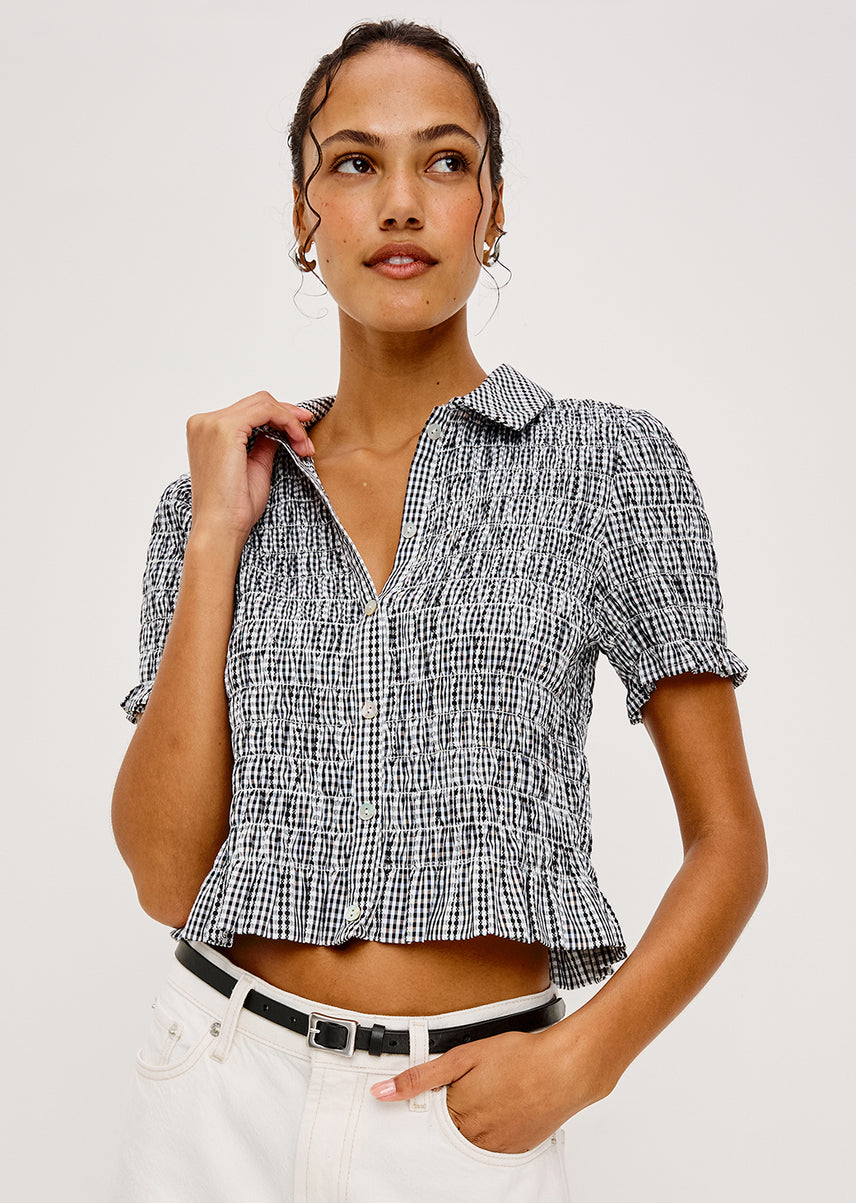 Woman wearing a black and white checkered blouse with a plain background