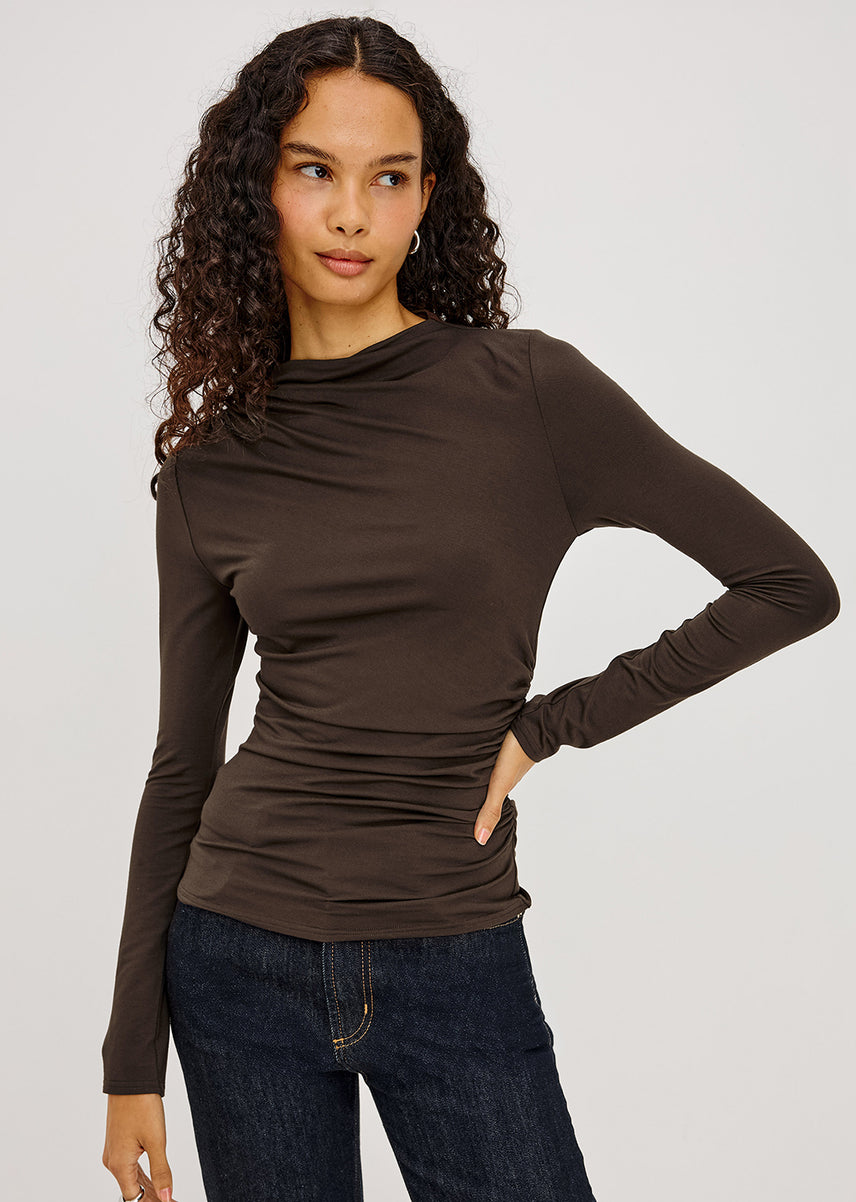 Woman wearing a brown long sleeve top with blue jeans