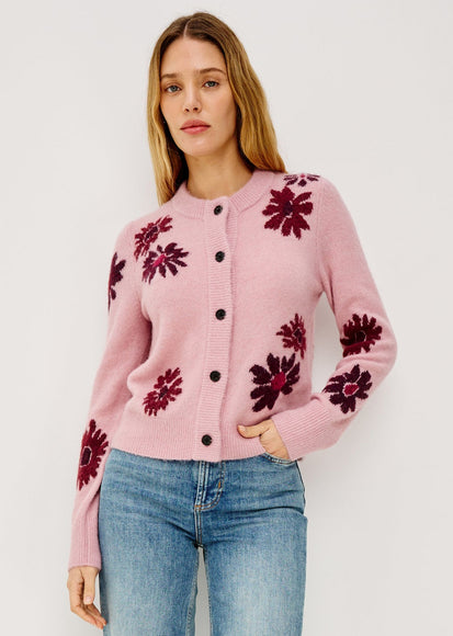 Woman wearing a pink cardigan with floral patterns on a white background