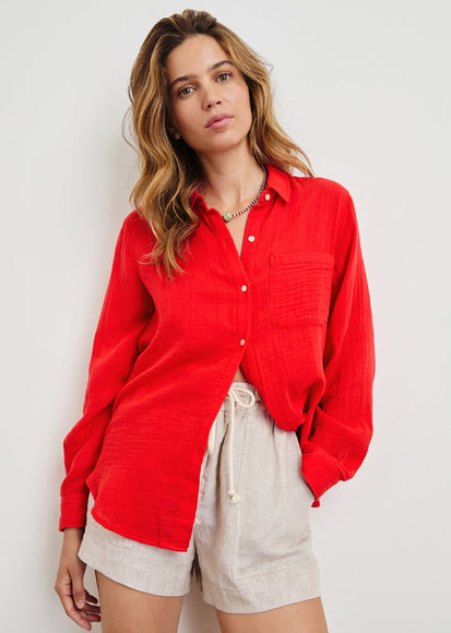 Woman wearing a red shirt and beige shorts against a white background