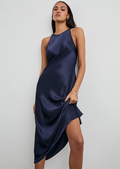 Woman wearing a navy blue satin dress against a white background