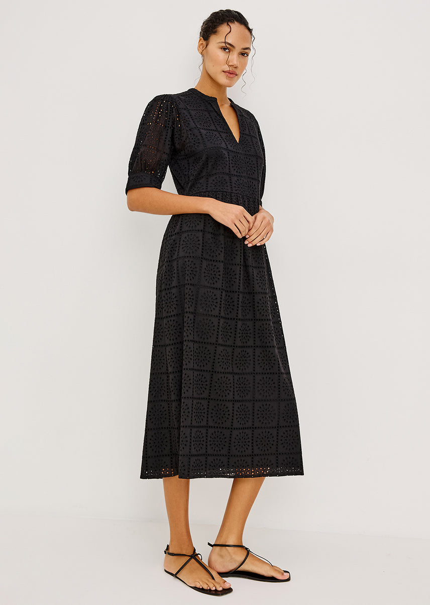 Woman wearing a black eyelet dress on a white background