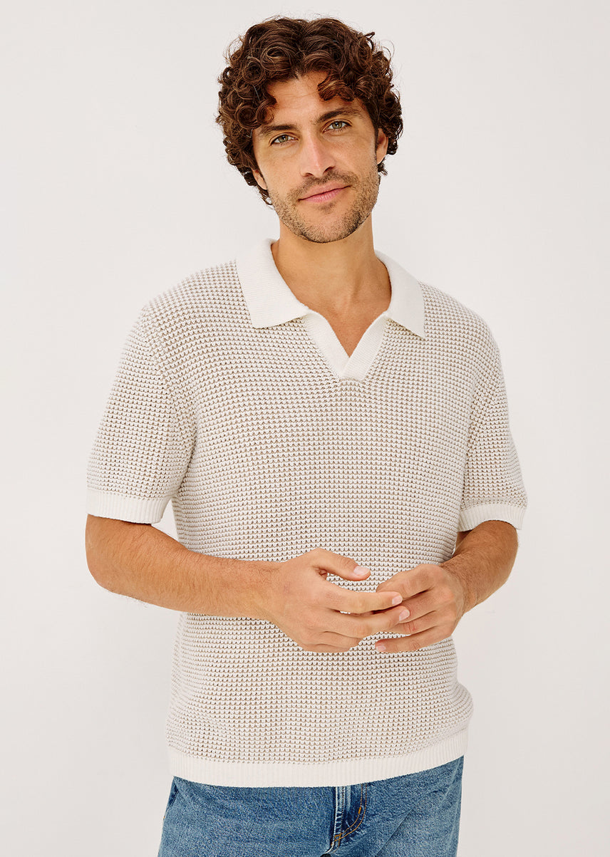 Man wearing a textured white shirt and blue jeans on a plain background