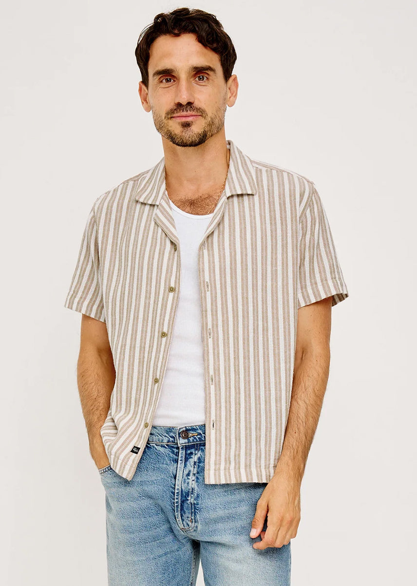 Man wearing a beige striped shirt with blue jeans