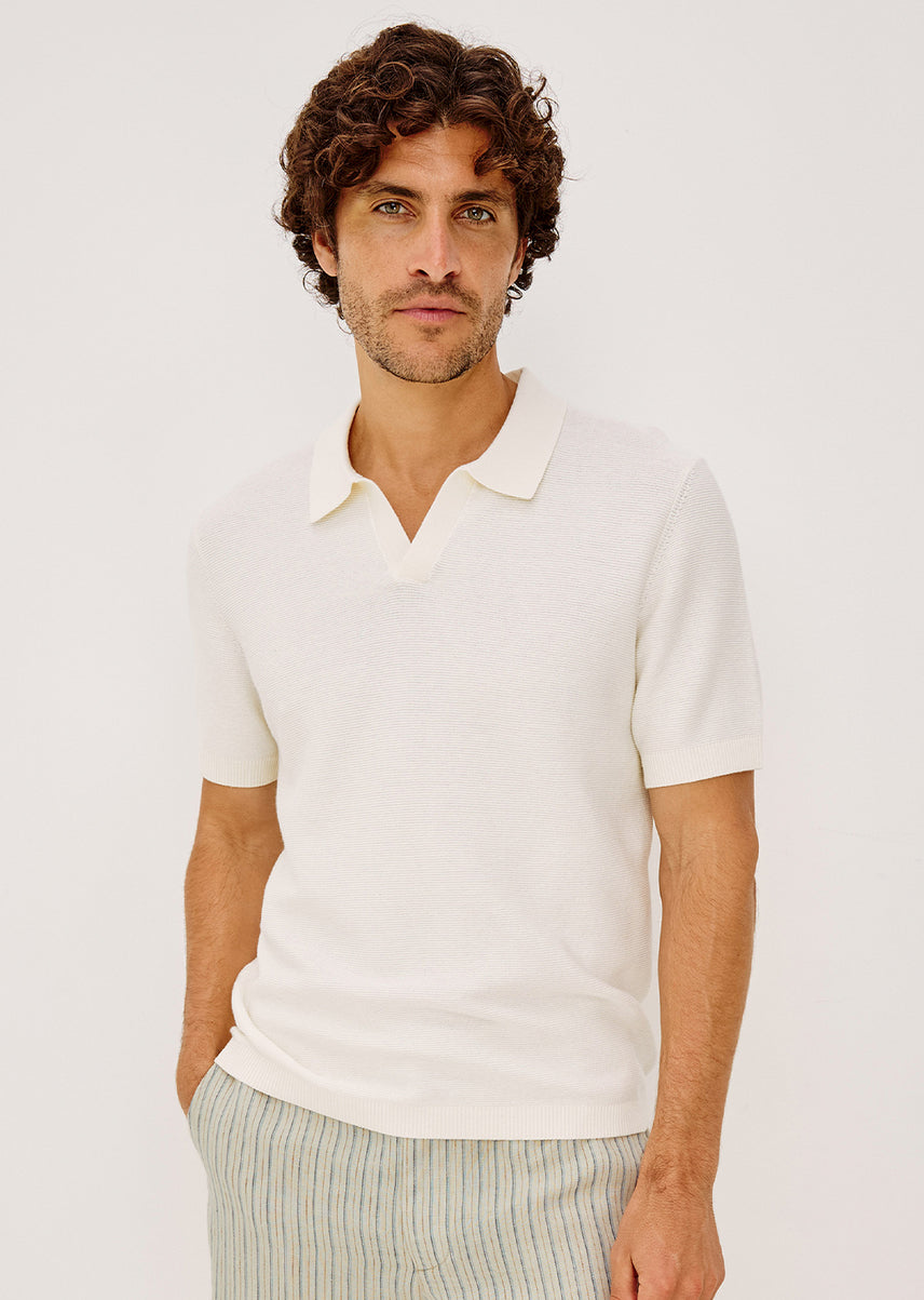 Man wearing a white polo shirt against a plain background