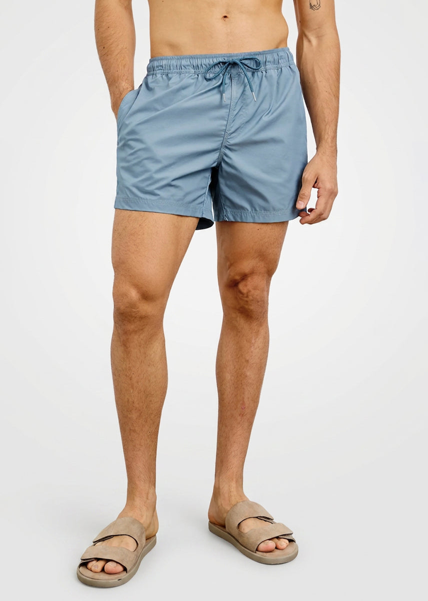 Person wearing light blue swim shorts on a white background