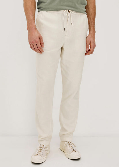 Man wearing white pants and a green shirt on a plain background